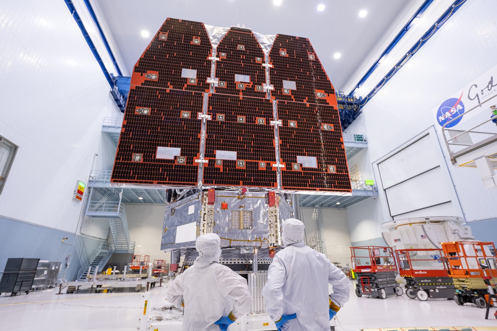 Technicians look up at the Roman Space Telescope’s deployed solar panels in NASA’s Goddard cleanroom before launch.