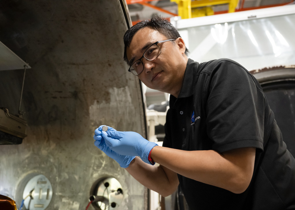 Yi Lin holds a small SPEARS coin-cell battery after thermal-vacuum testing at NASA Langley.