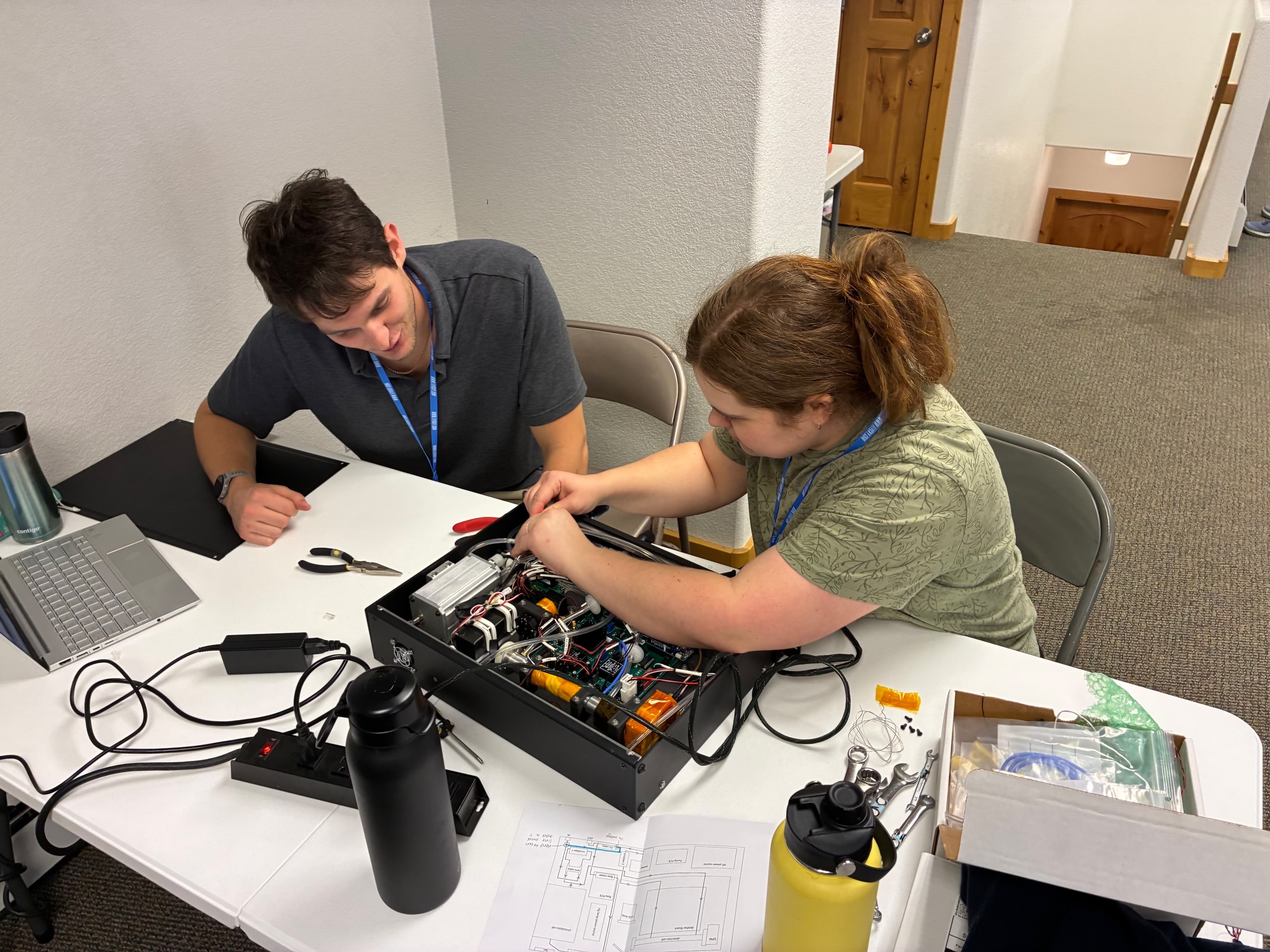 Two FarmFlux researchers work with the PIANO instrument at a table.