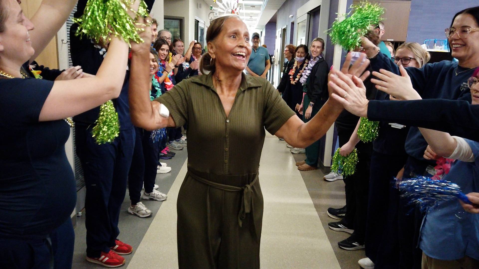 Maricela Olivas walks through a hallway of cheering caregivers as she leaves the hospital.